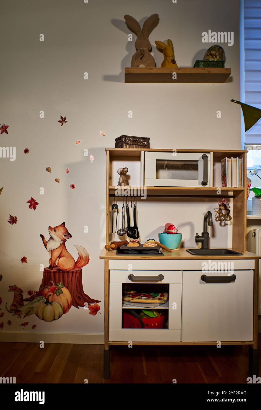 Küchenregal aus Holz mit verschiedenen Artikeln und skurrilen Wandaufklebern von Tieren und Blättern. Die Aufkleber wirken kreativ mit dem Inhalt des Regals Stockfoto