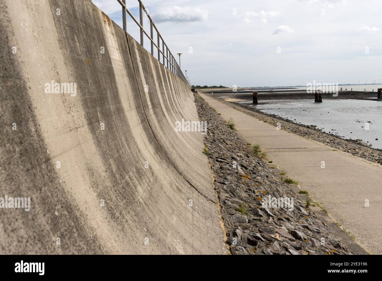 Ein robuster Uferwall in Eckwarderhörne, der Schutz vor den starken Gezeiten der Nordsee bietet, steht in starkem Kontrast zur natürlichen coasta. Stockfoto