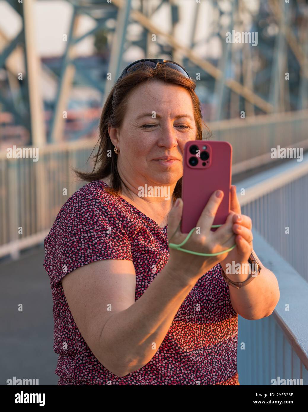 Frau mittleren Alters filmt auf dem Smartphone auf der Brücke, während sie neue Orte besucht. Dresden. Deutschland Stockfoto