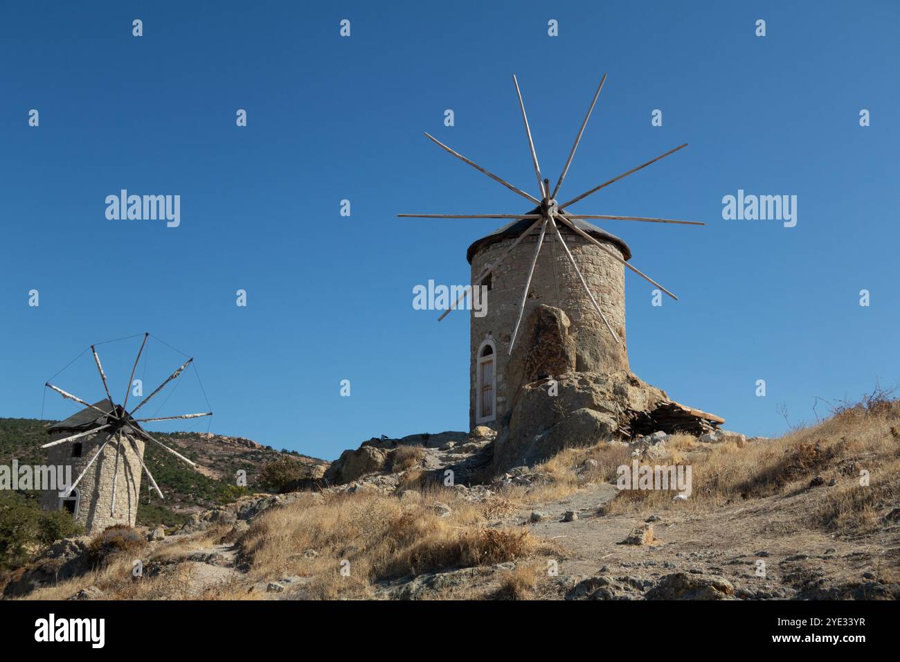 Blick auf zwei alte Windmühlen vor klarem blauem Himmel in der Nähe von Fosca Türkei Stockfoto