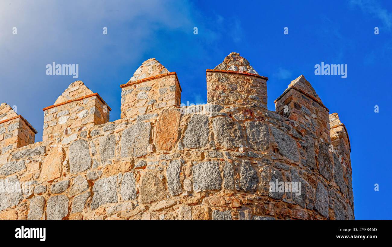 Avila, Spanien - 11. Februar 2023: Hoher Teil einer mittelalterlichen befestigten Mauer vor einem blauen Himmel. Stockfoto