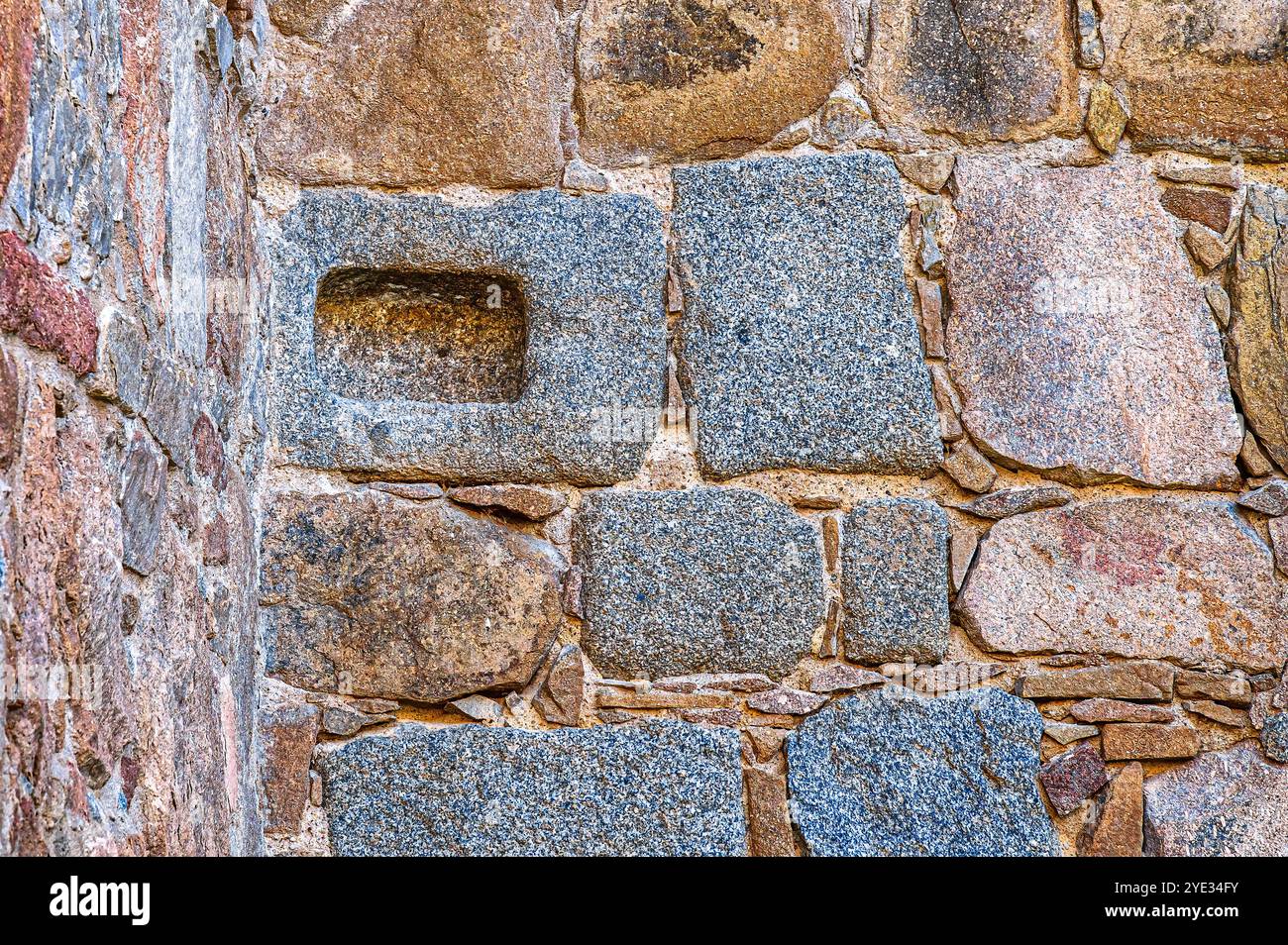 Avila, Spanien - 11. Februar 2023: Ein rechteckiges, geschnitztes Loch in einem Steinblock, der Teil einer mittelalterlichen Gebäudemauer ist. Stockfoto