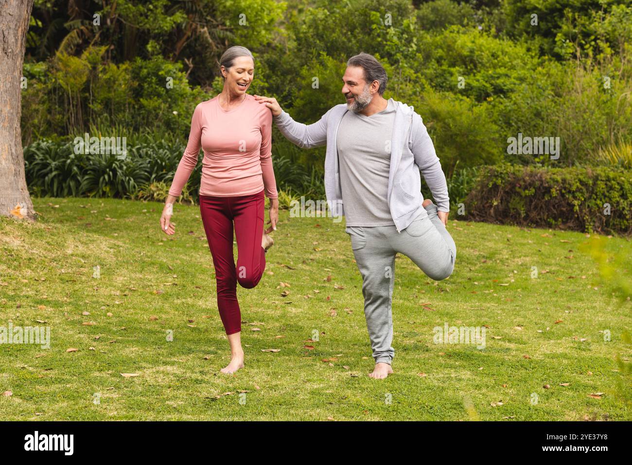 Reife Paare genießen gemeinsam Outdoor-Übungen und balancieren auf einem Bein im Park Stockfoto