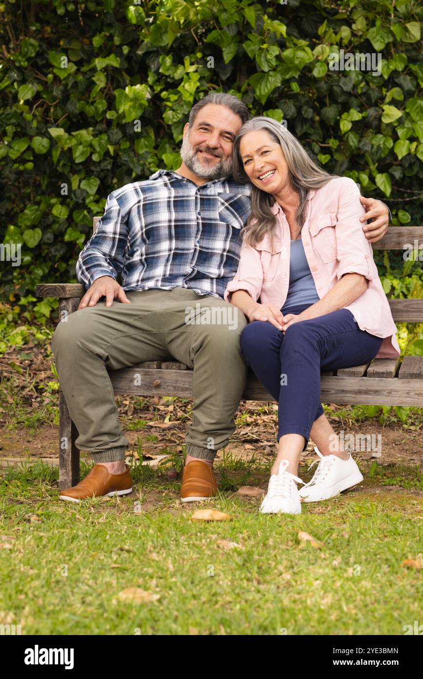Glückliches, reifes Paar, das auf der Parkbank sitzt und friedliche Momente im Freien genießt Stockfoto