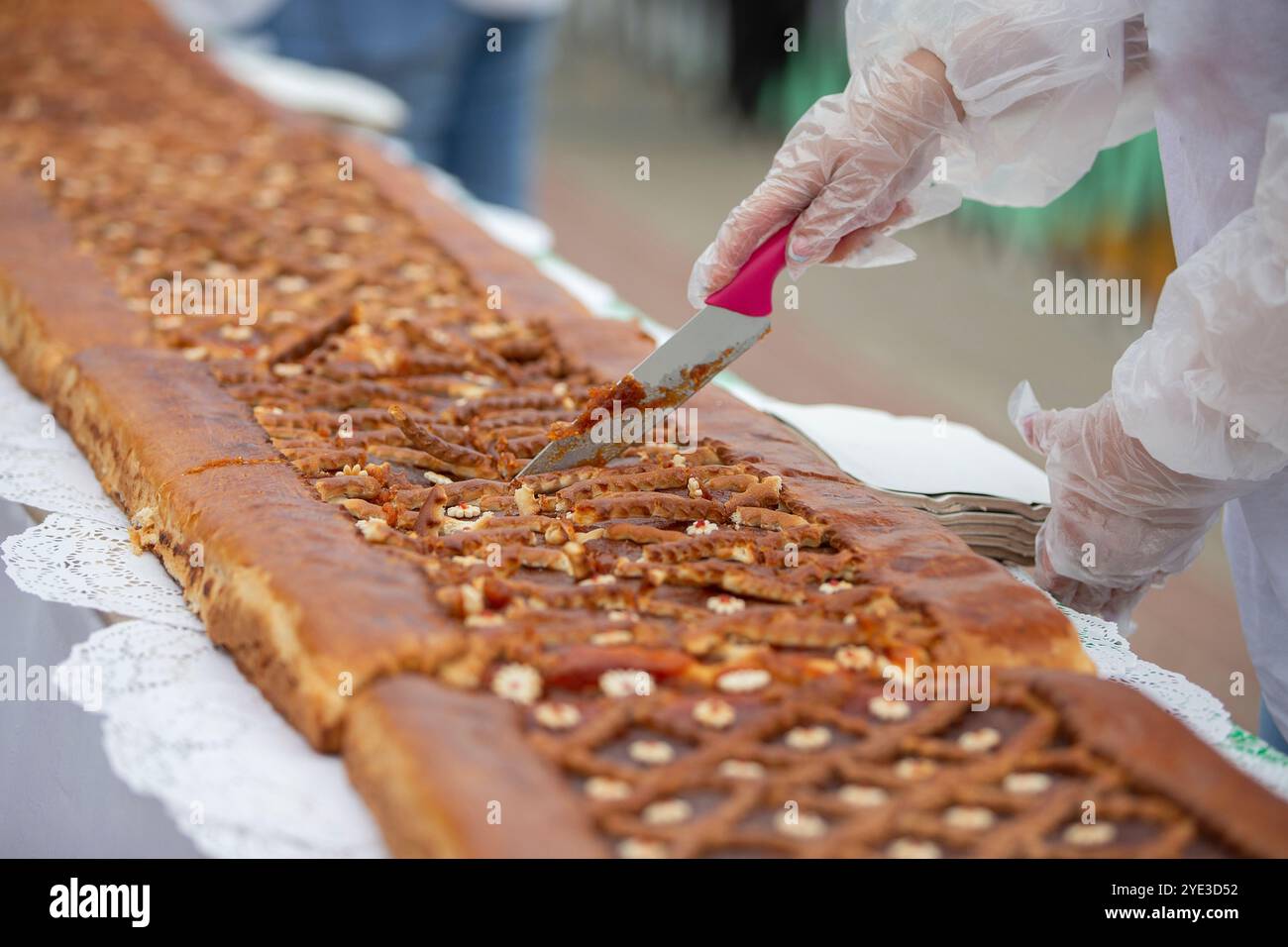 Ein Kochmesser schneidet Hefekuchen auf einem Industrieband. Stockfoto