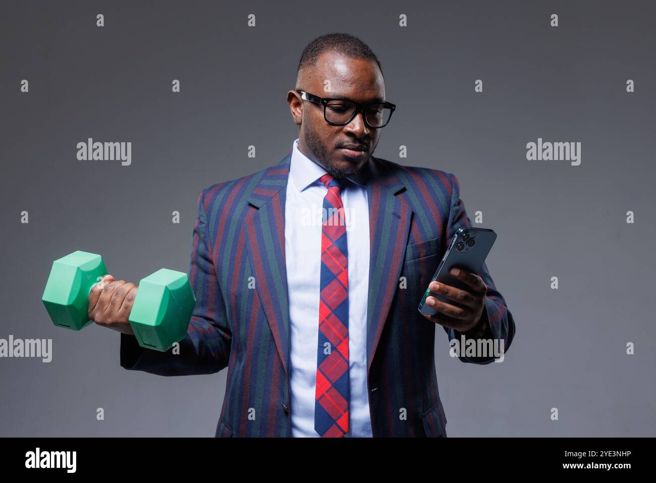 Afrikanischer Geschäftsmann in Anzug arbeitet online mit dem Telefon in der Hand und macht gleichzeitig Sport, Business und Sport Stockfoto