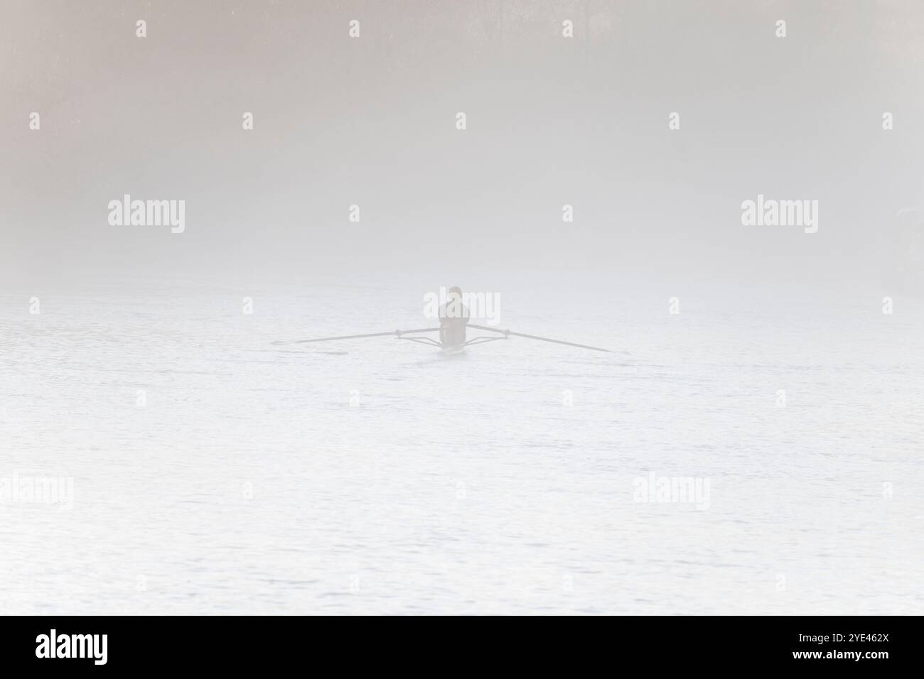 Einsamer Ruderer im Nebel, die Themse bei Iffley Lock und flussabwärts von Oxford. Es ist früh an einem nebeligen Herbstmorgen, aber man kann alle Arten von Rudern auf diesem Flussabschnitt sehen, zu jeder Jahreszeit, bei Regen oder Sonnenschein. Engagierte Seelen. Auch in diesem Fall fast unsichtbar. Stockfoto