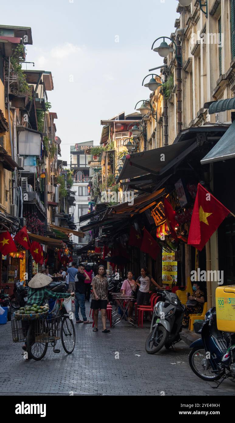 Hanoi, Vietnam: Alltag, Verkehr und Skyline in den überfüllten Straßen des Zentrums der Hauptstadt, mit Autos und Motorrädern, die mit voller Geschwindigkeit vorbeifahren Stockfoto