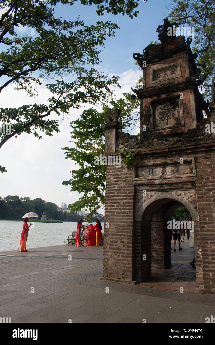 Hanoi, Vietnam: Frau mit Regenschirm vor dem Turtle Tower (Thap Rua), einem kleinen Turm, der 1886 in der Mitte des Sword Lake (Hoan Kiem Lake) errichtet wurde Stockfoto