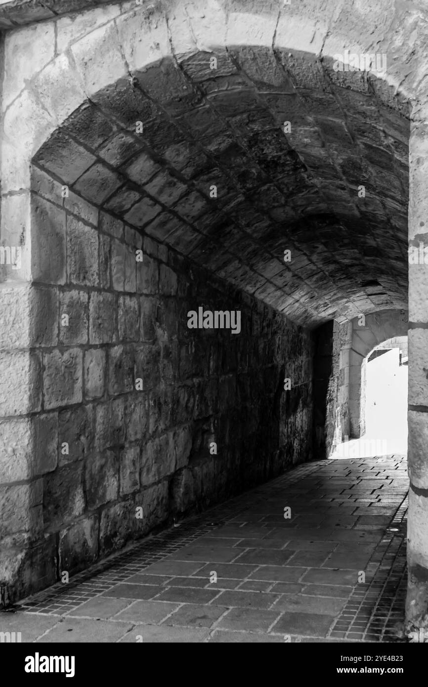 Historischer Steinbogen, der zum sonnendurchfluteten Pfad führt Stockfoto Historischer Steinbogen, der zum sonnendurchfluteten Pfad führt Stockfoto