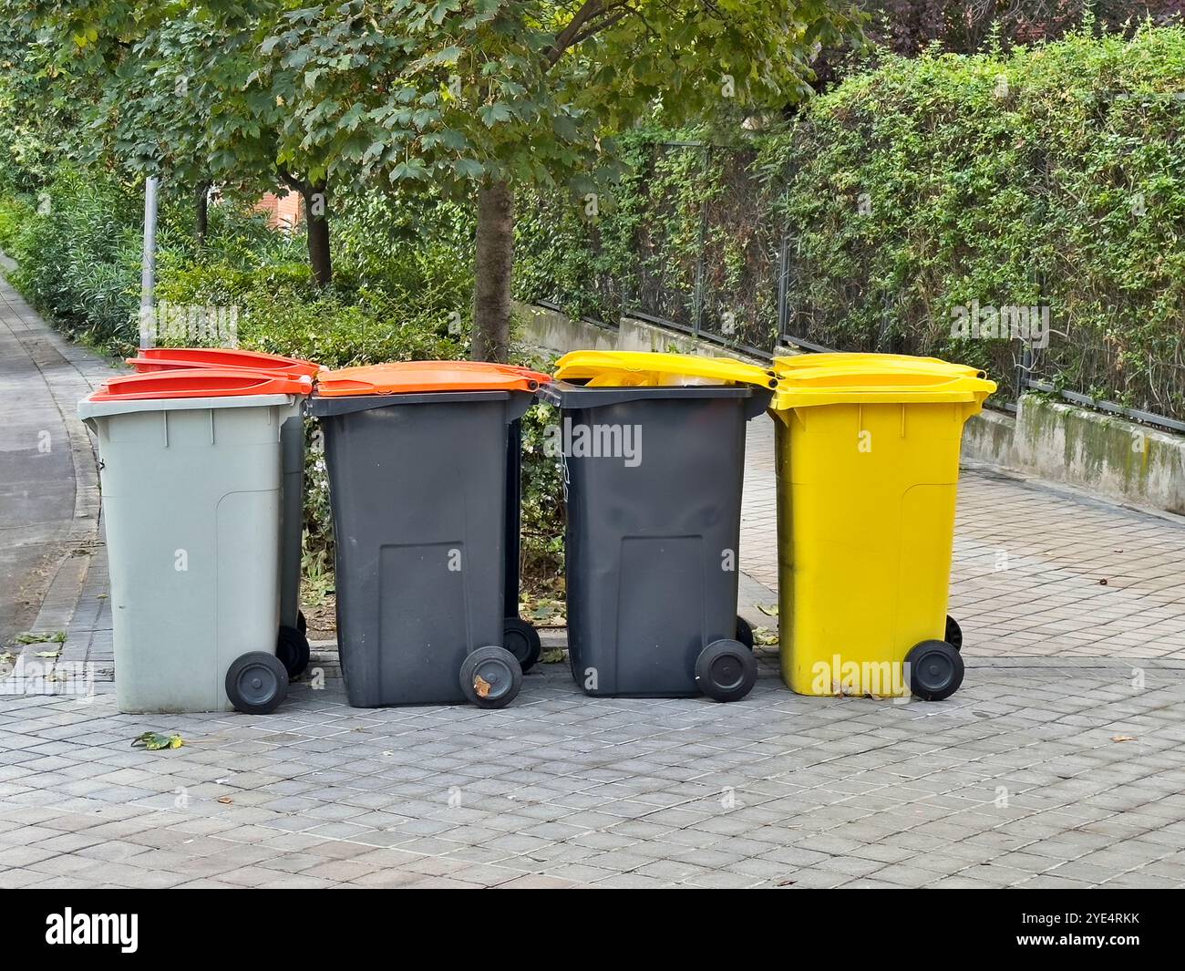 Vier Abfallbehälter stehen auf dem Bürgersteig. Die Mülleimer haben verschiedene Farben und Größen Stockfoto