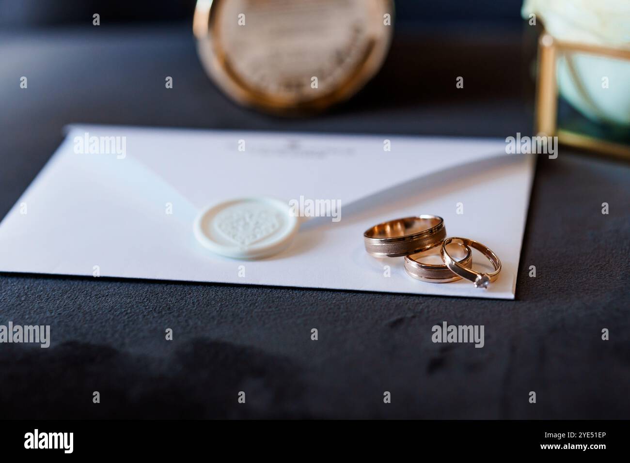 Elegant angeordnete Hochzeitsringe und versiegelte Einladung auf Samthintergrund. Stockfoto