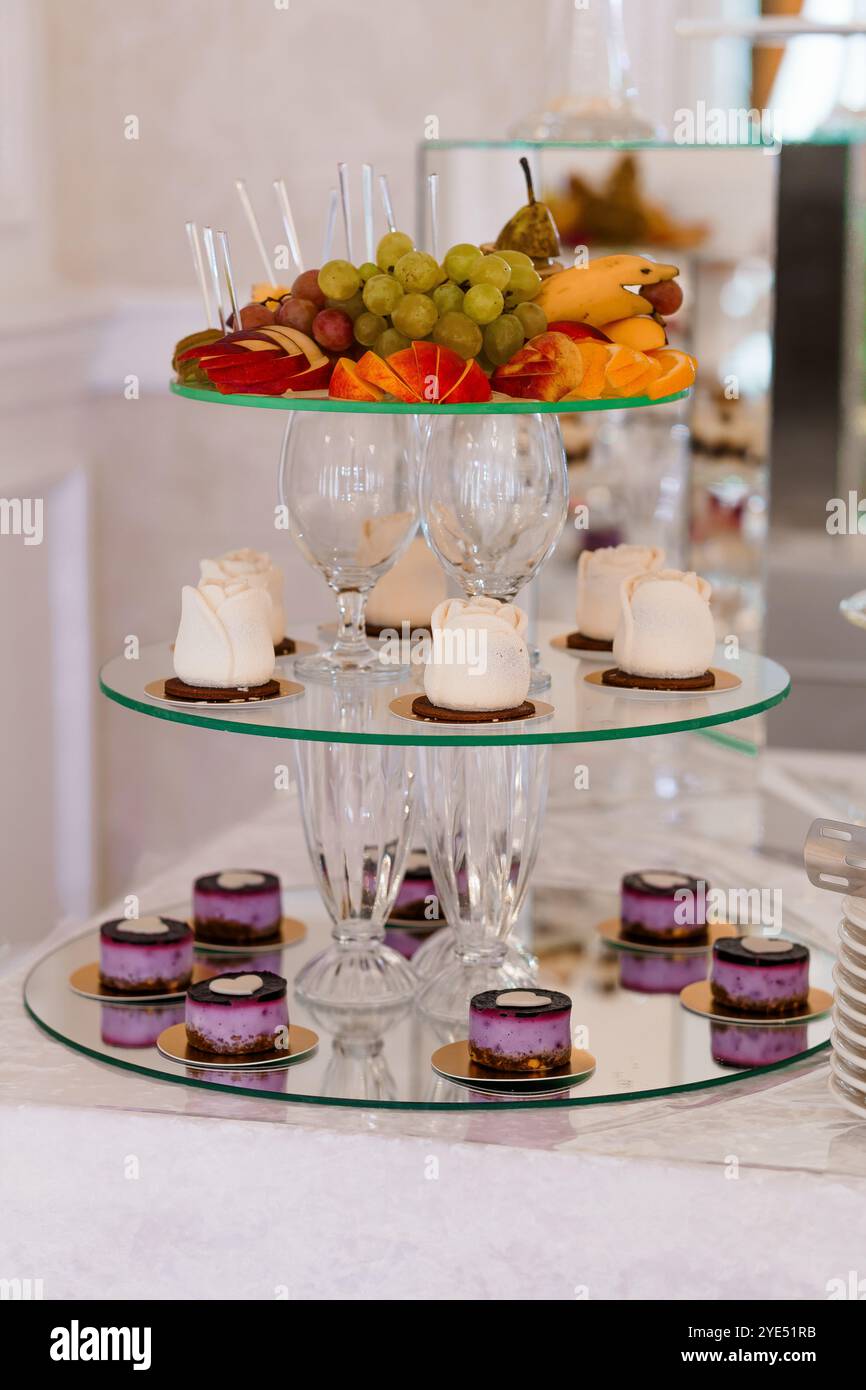 Elegante Dessertpräsentation mit Obst und Gebäck auf Glasständern. Stockfoto