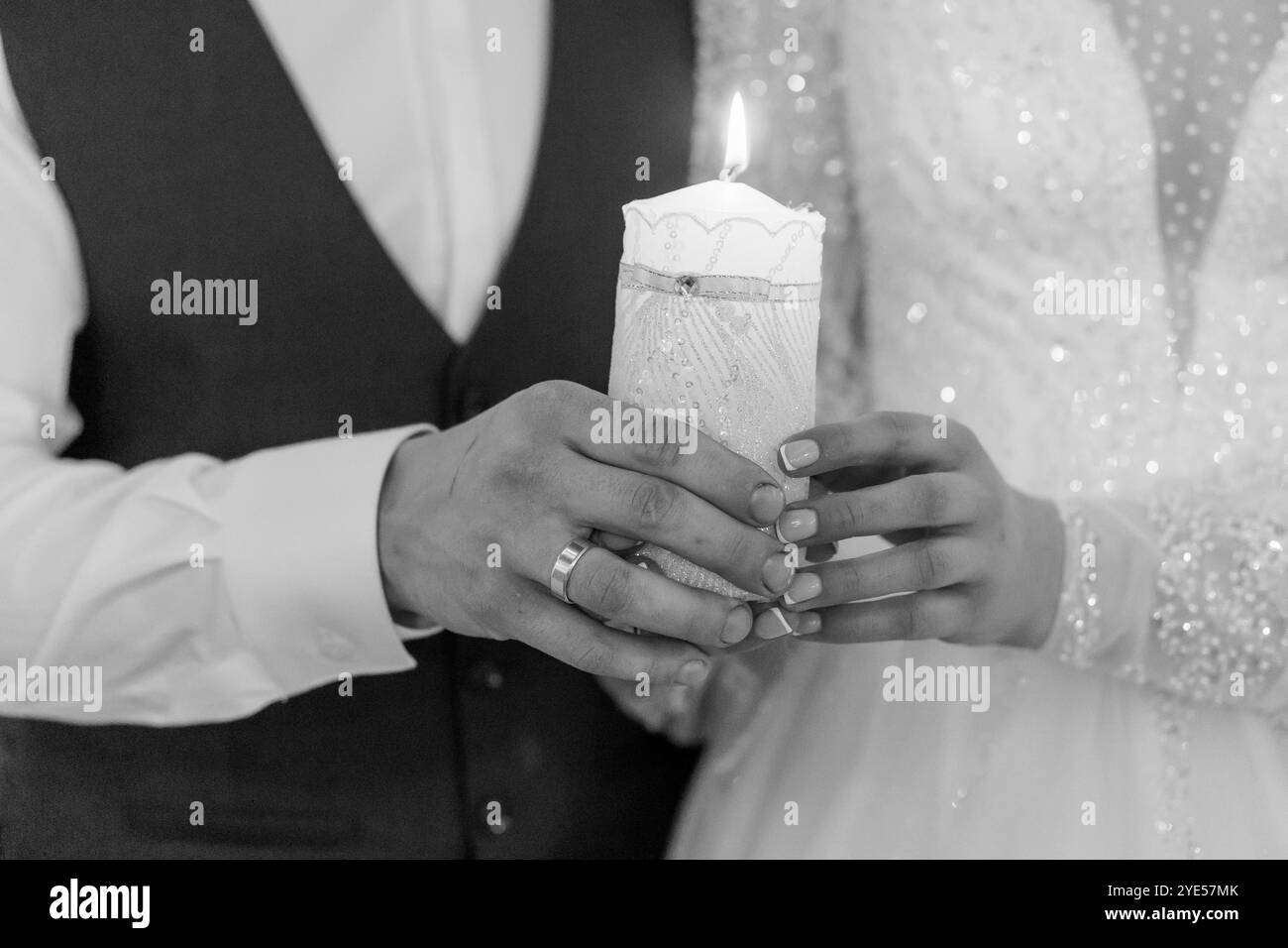 Romantische Zeremonie bei Kerzenschein mit Braut und Bräutigam, die die Unity Candle halten. Stockfoto