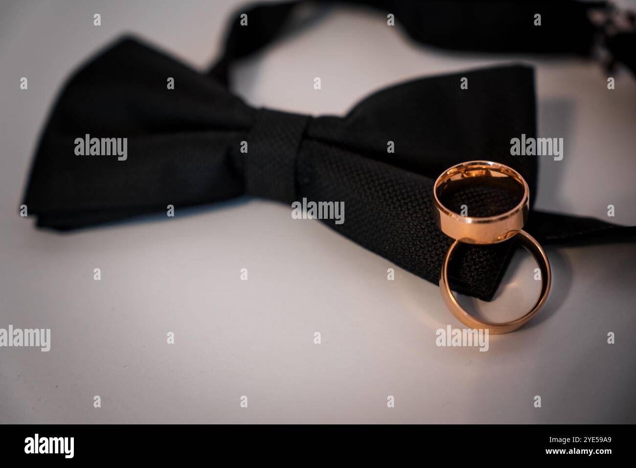 Elegantes Design mit Ehering und Schleife auf einer sauberen Oberfläche. Stockfoto