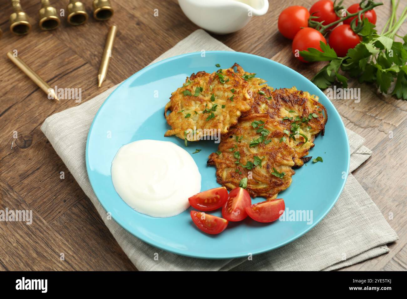 Leckere Kartoffelpfannkuchen, Menora und Kerzen auf Holztisch, Nahaufnahme. Hanukkah festliches Essen Stockfoto