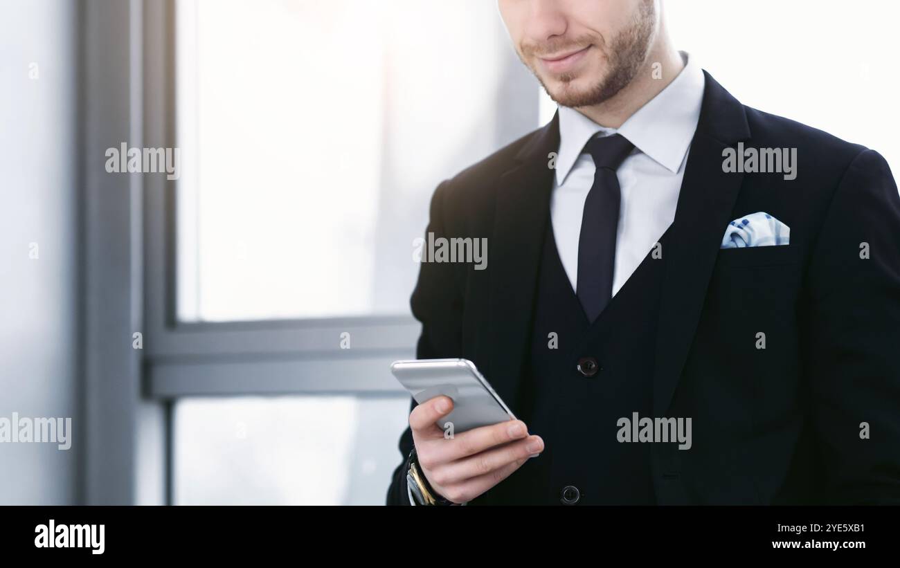 Lächelnder Mann hält und schaut auf das Telefon Stockfoto