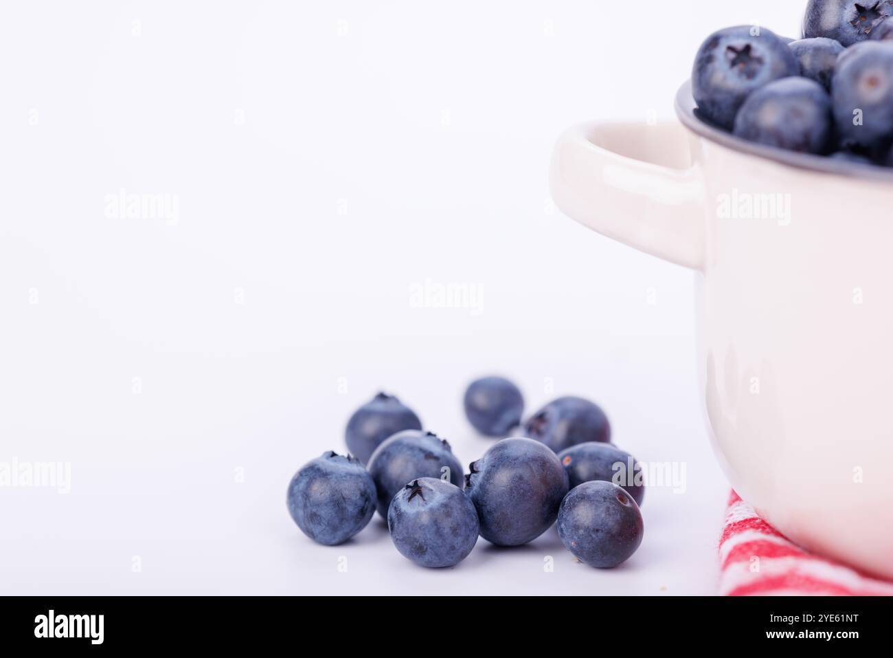 Eine Nahaufnahme eines Keramiktopfes gefüllt mit Heidelbeeren auf einem unendlichen weißen Hintergrund mit viel Liebe zum Detail Stockfoto