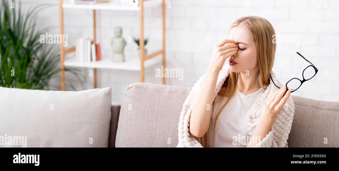 Müde junge Blonde massiert Nasenbrücke Stockfoto