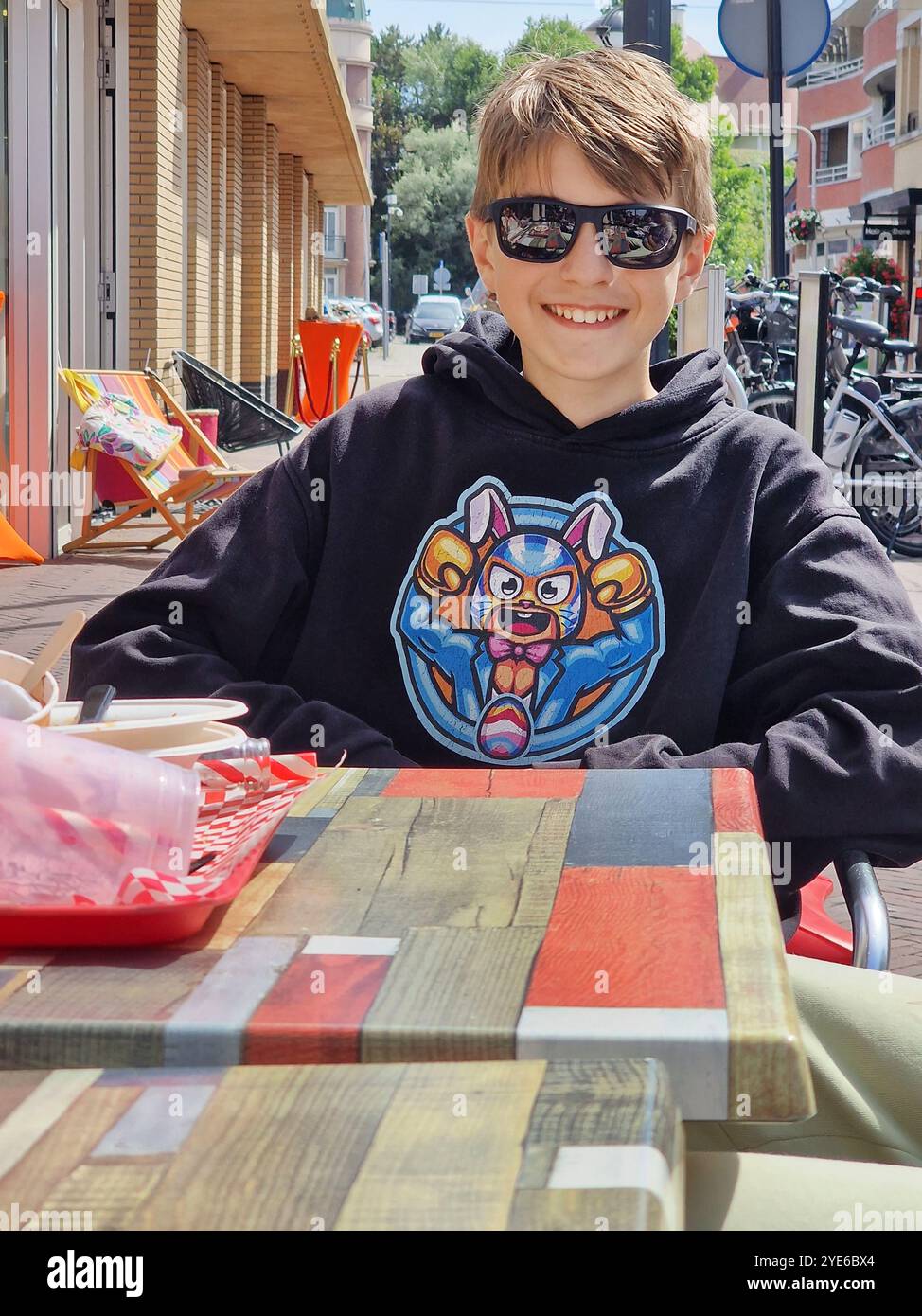 Glücklicher Teenager, der draußen an einem Tisch in einem Fast-Food-Restaurant sitzt Stockfoto