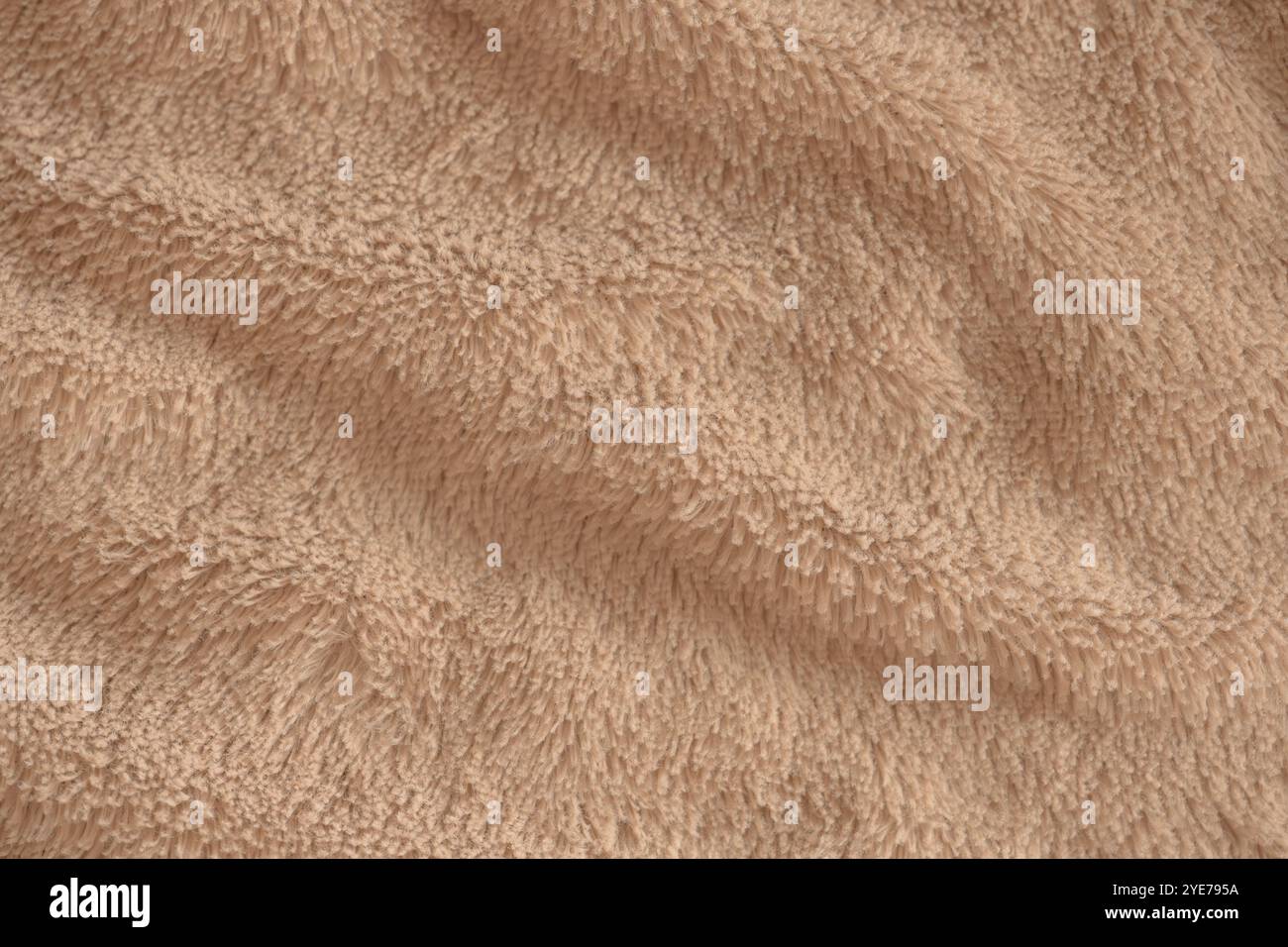 Beige zart weicher Hintergrund aus Plüschstoff. Textur aus weichem Kunstpelzgewebe mit schönen Falten, Nahaufnahme, hohe Auflösung. Stockfoto