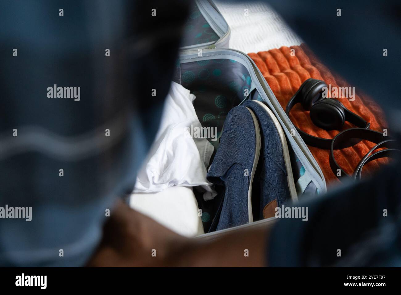 Afroamerikanischer Mann, Koffer mit Schuhen und Kopfhörern für Urlaubsreisen zu Hause Stockfoto
