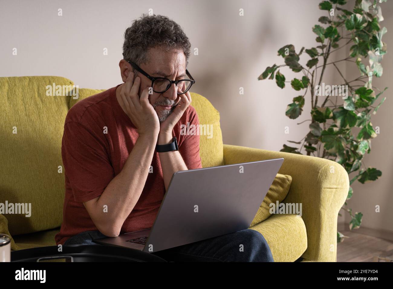 Mann mittleren Alters, der digitale Müdigkeit erlebt, während er von zu Hause aus arbeitet. Natürliches Lifestyle-Porträt eines Reifen Berufs, der mit Fernarbeiten beschäftigt ist Stockfoto