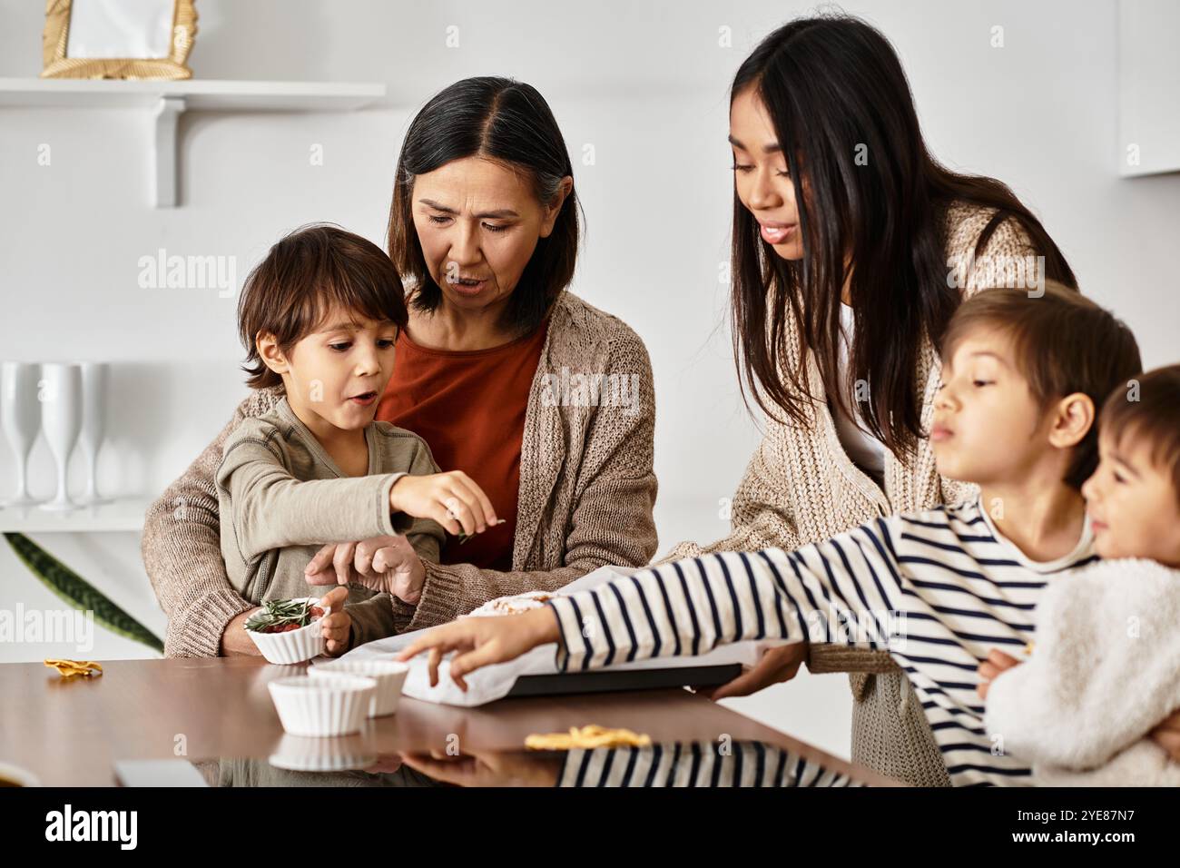 Eine fröhliche asiatische Familie versammelt sich, um festliche Köstlichkeiten zu backen und im Winter mit Lachen und Freude Erinnerungen zu schaffen. Stockfoto