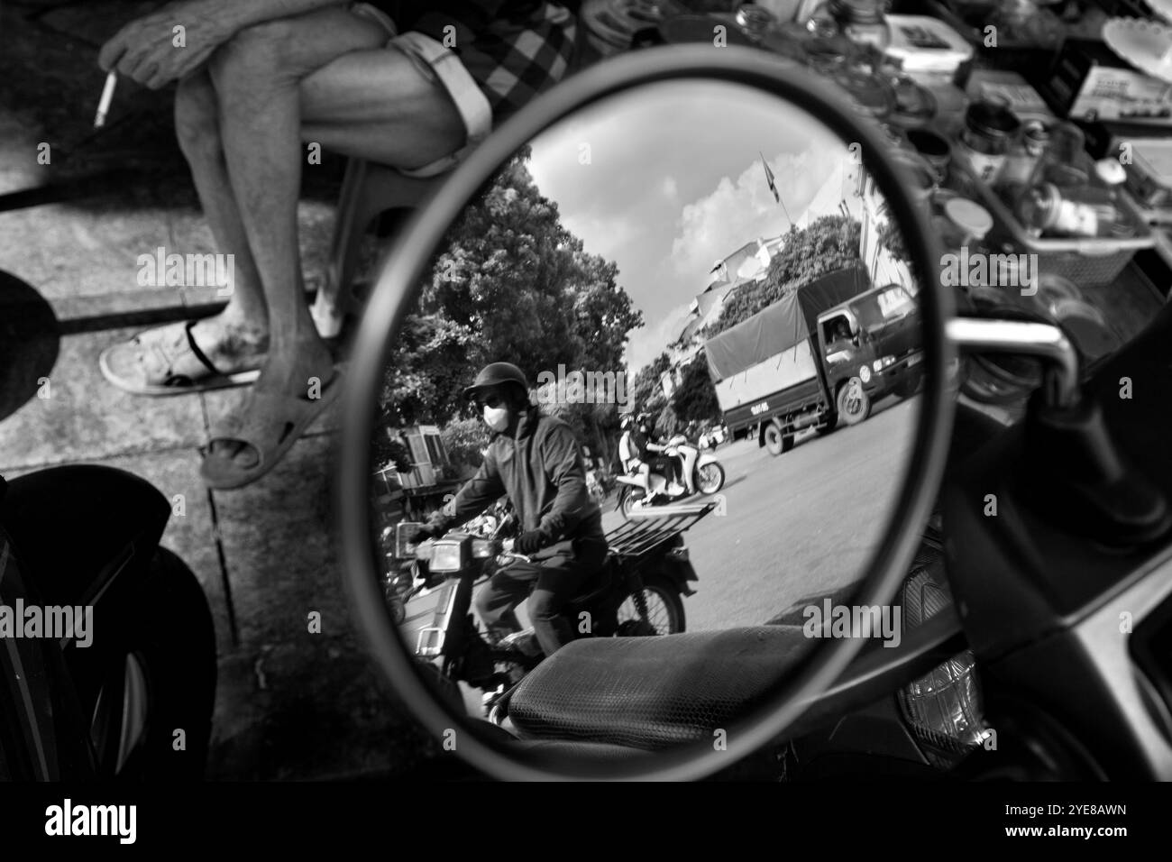 Reflexion einer Person, die einen Roller mit einem Mann fährt, der eine Zigarette in Hanoi, Vietnam, hält Stockfoto
