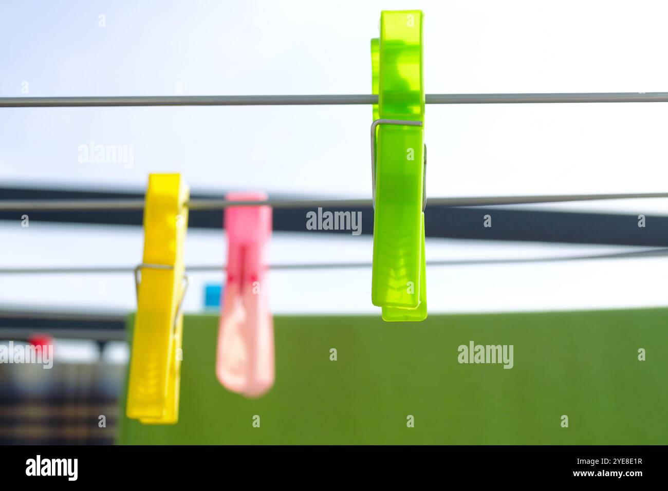 Trocknen von Kleidung bei Wind und Sonne: Mehrfarbige Kunststoffkleideräume hängen an verschiedenen Metallstäben eines Outdoor-Trockenregals, Nahaufnahme Stockfoto