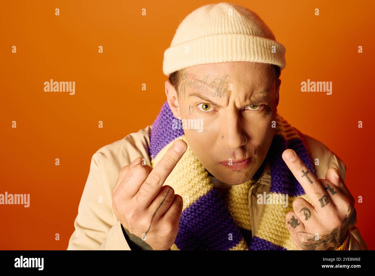 Ein junger Mann zeigt seine Tattoos und zeigt eine kühne Geste, die Haltung und Stil zum Ausdruck bringt. Stockfoto