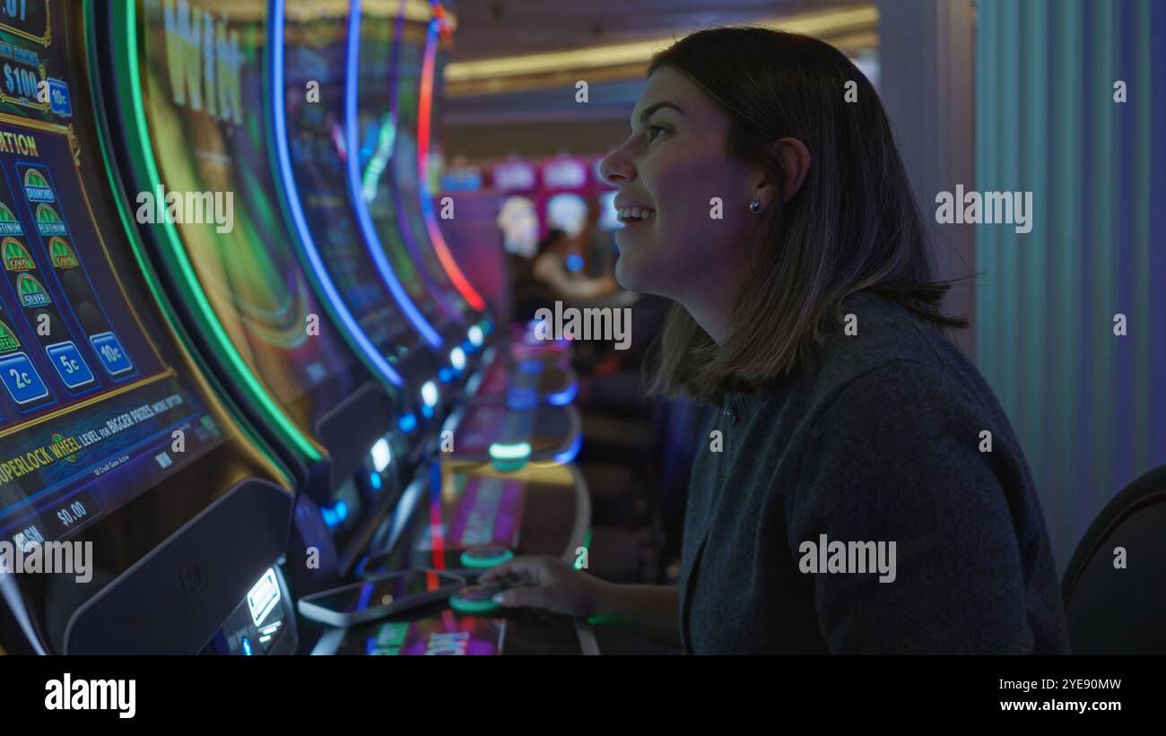 Frau lächelt an Spielautomaten in einem lebhaften Las vegas Casino und bietet eine lebhafte Spielatmosphäre, voller Spannung und bunten Lichtern Stockfoto