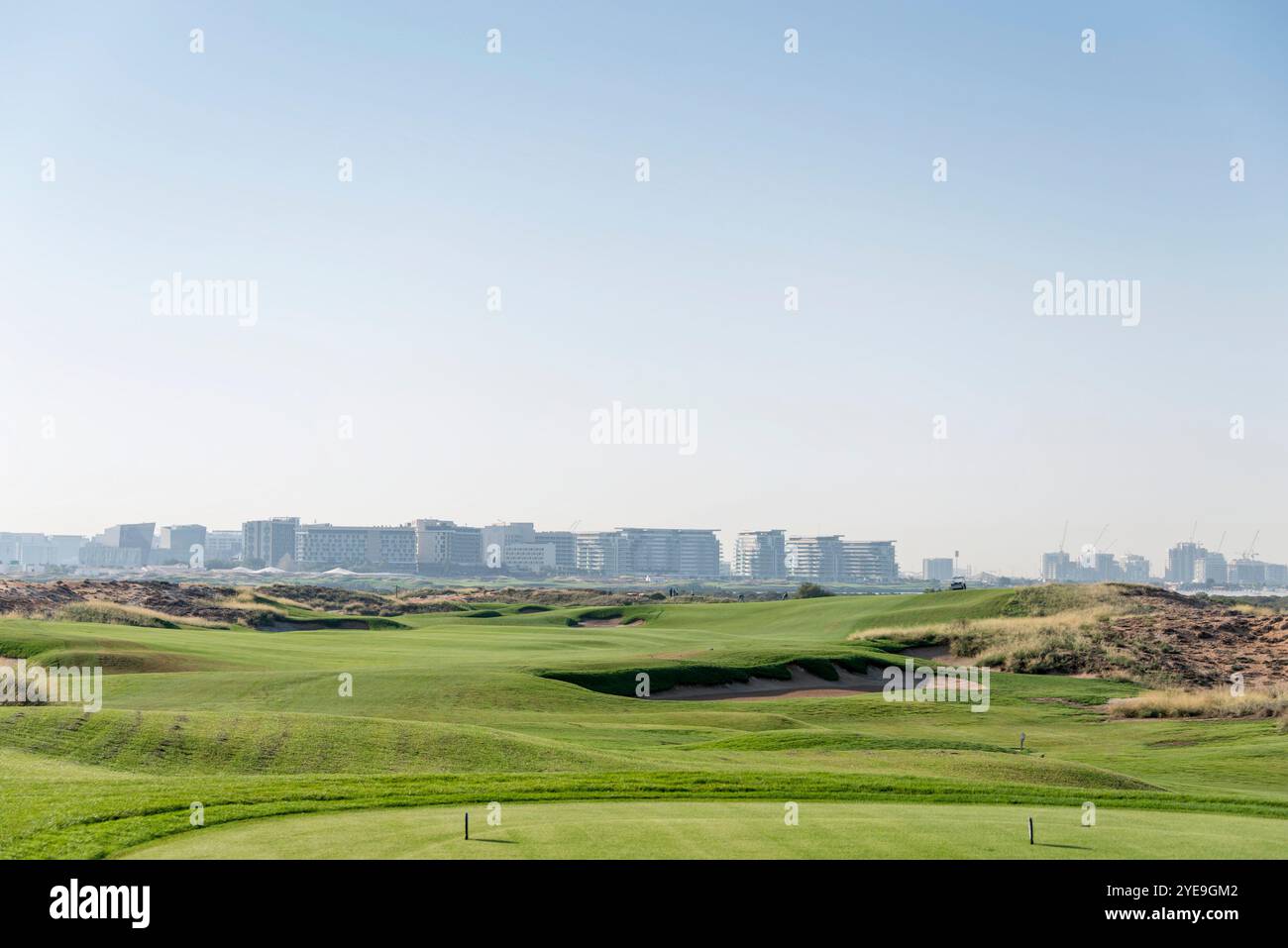 Golfplatzlandschaft an einem sonnigen Tag mit Wohnhäusern in der Skyline; Abu Dhabi, Vereinigte Arabische Emirate Stockfoto