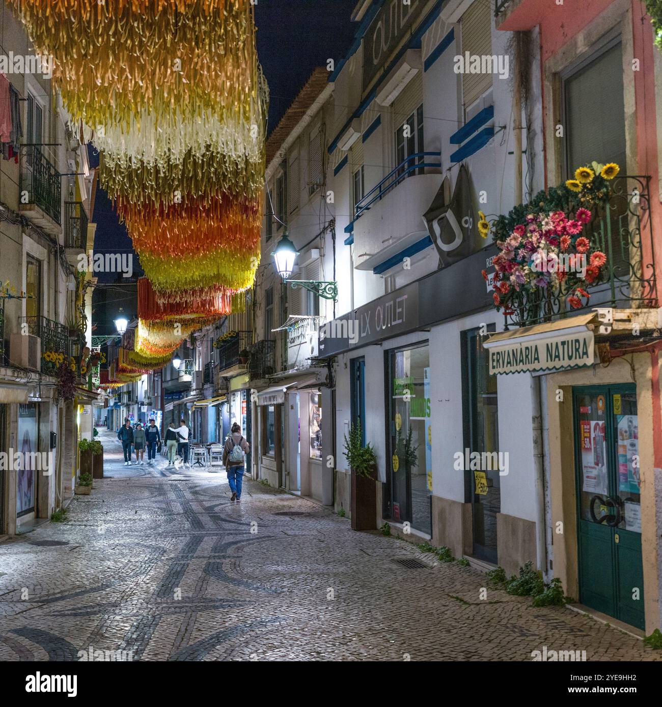 Fußgänger in einem nächtlichen Einkaufsviertel in Setubal, Portugal. Setubal ist eine geschäftige Hafen- und Industriestadt, die eine ausgedehnte... Stockfoto