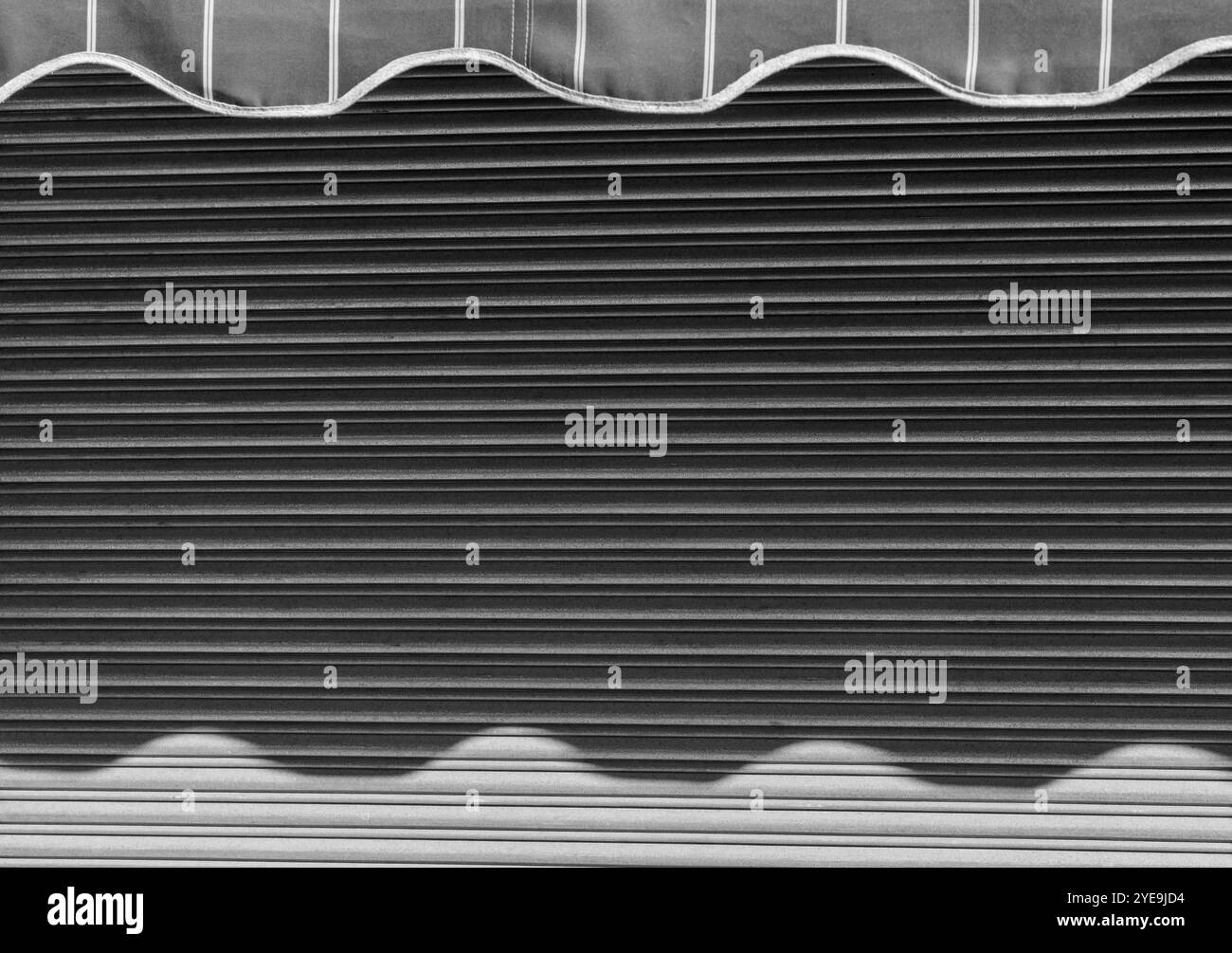 Abstrakte Wellen Reflexionen: Sonnenbeschienene Schatten auf Metallmarkise mit Streifenmuster. Stockfoto