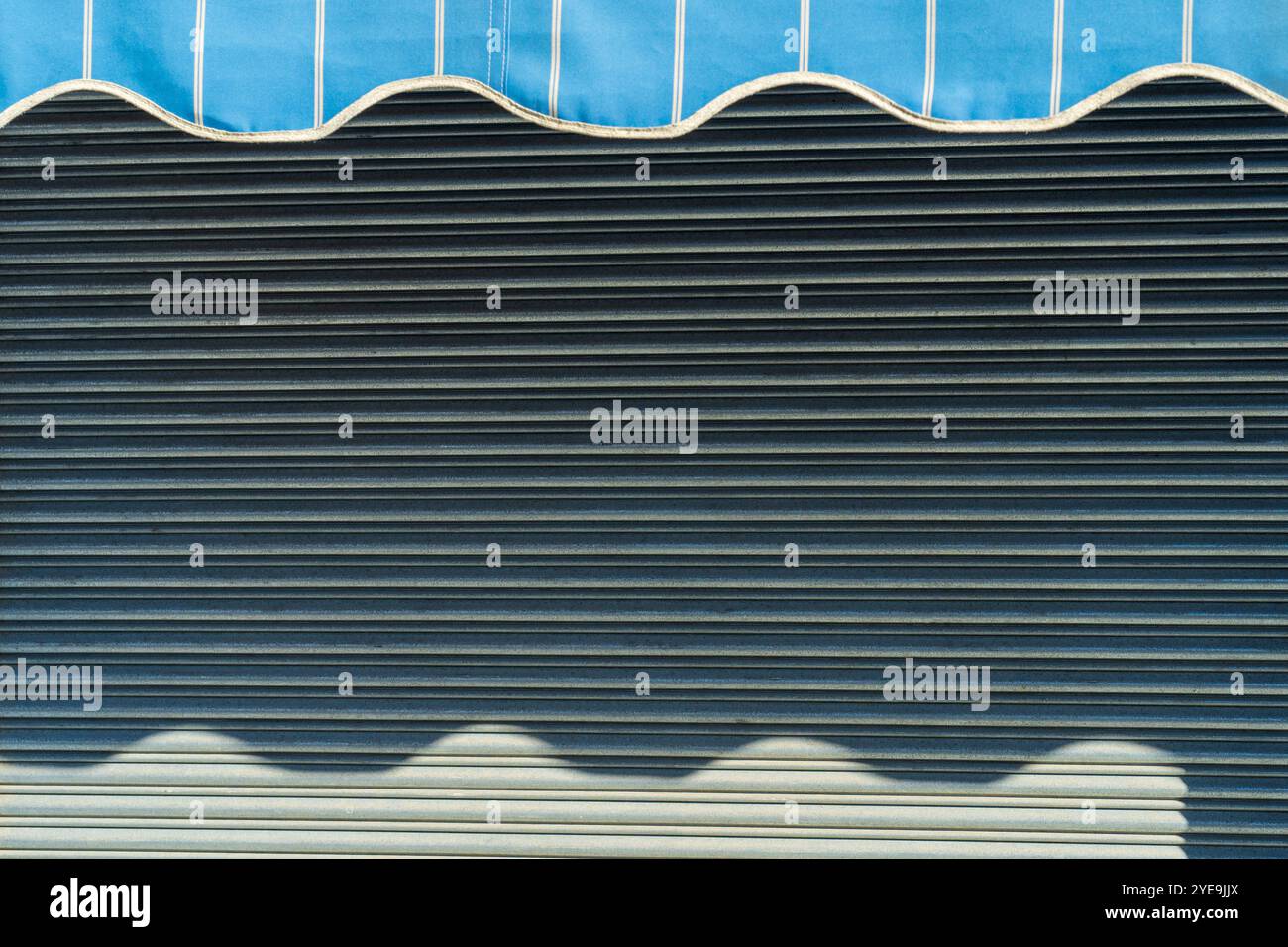Abstrakte Wellen Reflexionen: Sonnenbeschienene Schatten auf Metallmarkise mit Streifenmuster. Stockfoto