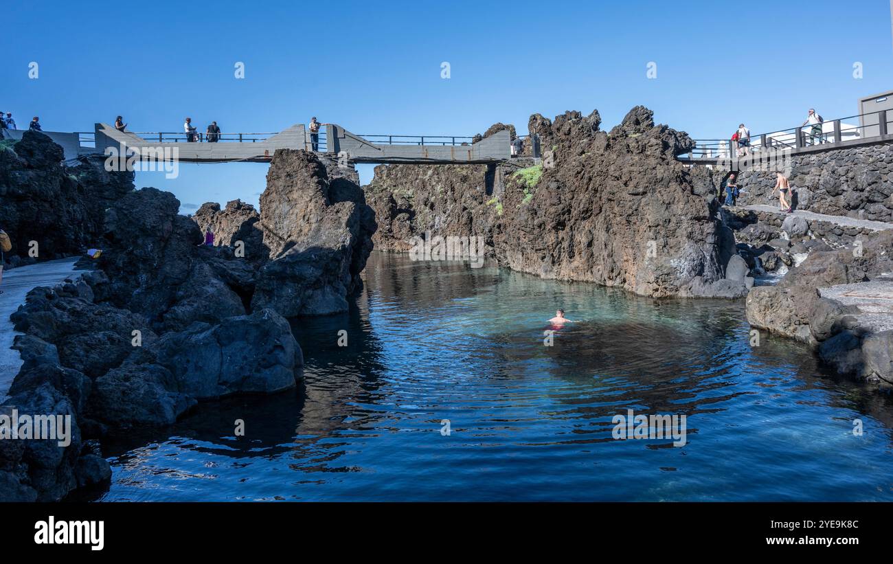 Touristen, die von einem erhöhten Fußweg entlang der Küste von Porto Moniz auf der Insel Madeira, Portugal; Porto Moniz, Madeira, Portugal Stockfoto