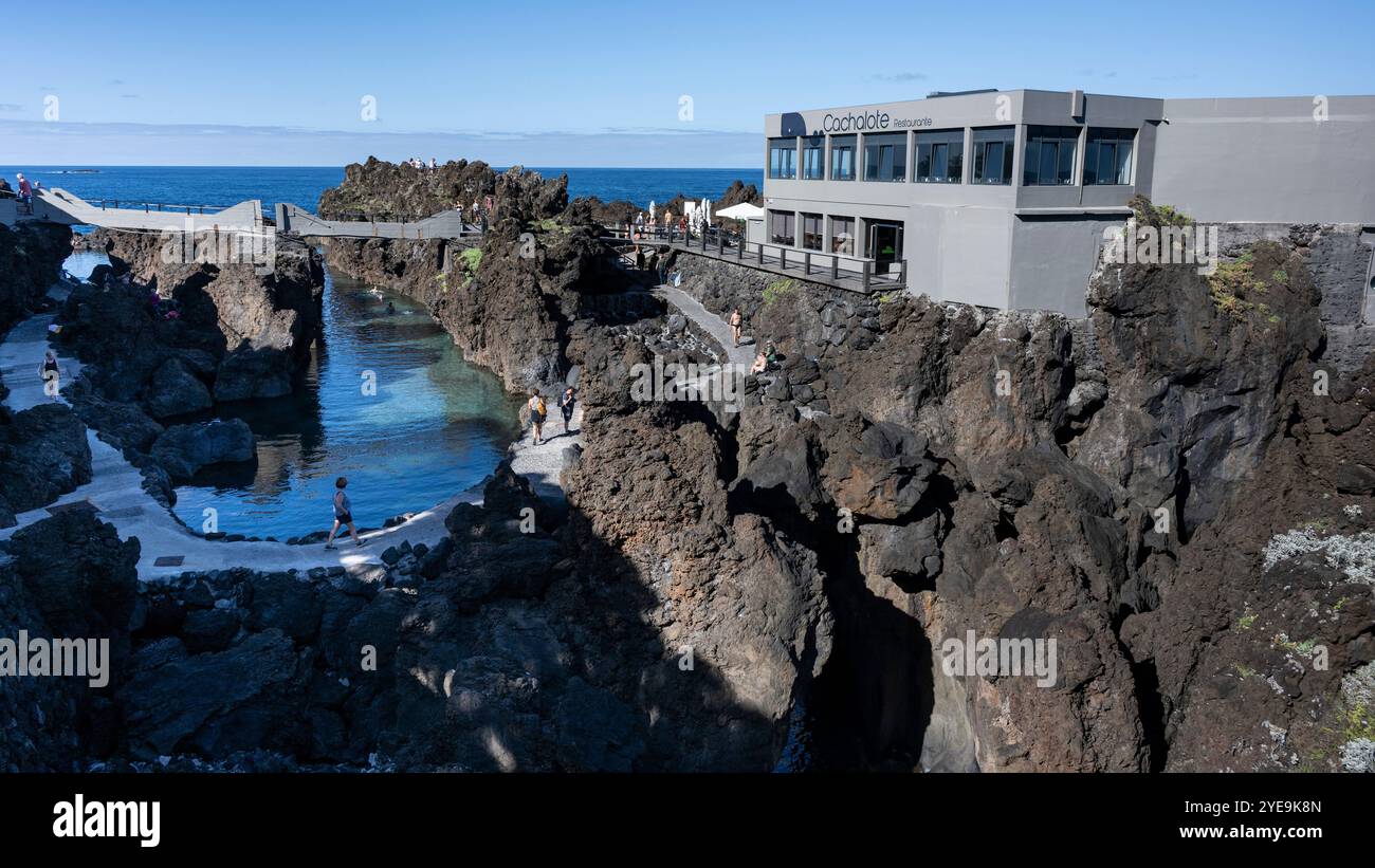 Touristen, die von einem erhöhten Fußweg entlang der Küste von Porto Moniz auf der Insel Madeira, Portugal; Porto Moniz, Madeira, Portugal Stockfoto