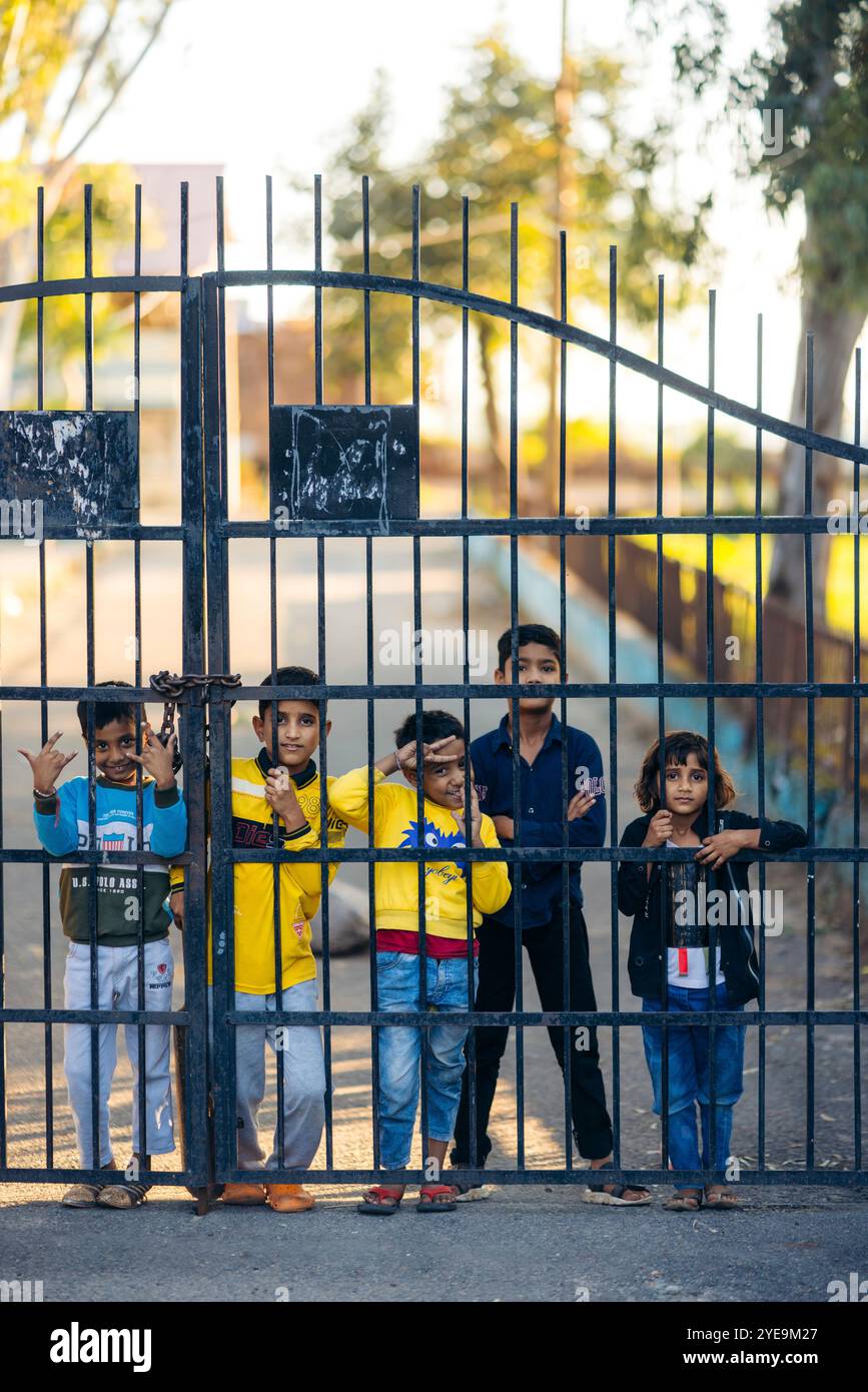 Kinder stehen durch einen Metallzaun und posieren für die Kamera: Jammu, Jammu und Kaschmir, Indien Stockfoto