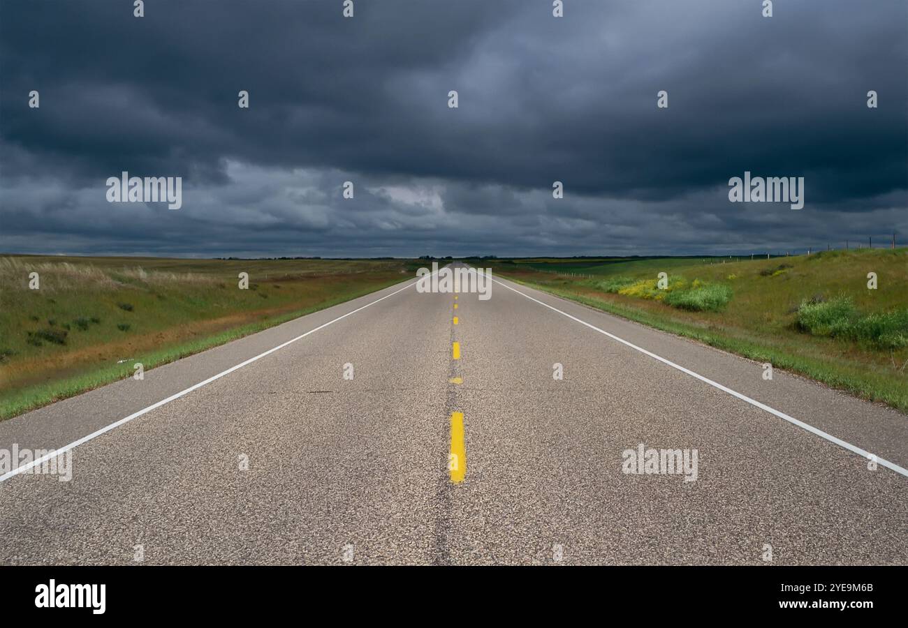 Die Landstraße führt unter Gewitterwolken in Alberta, Kanada, zum Horizont Stockfoto