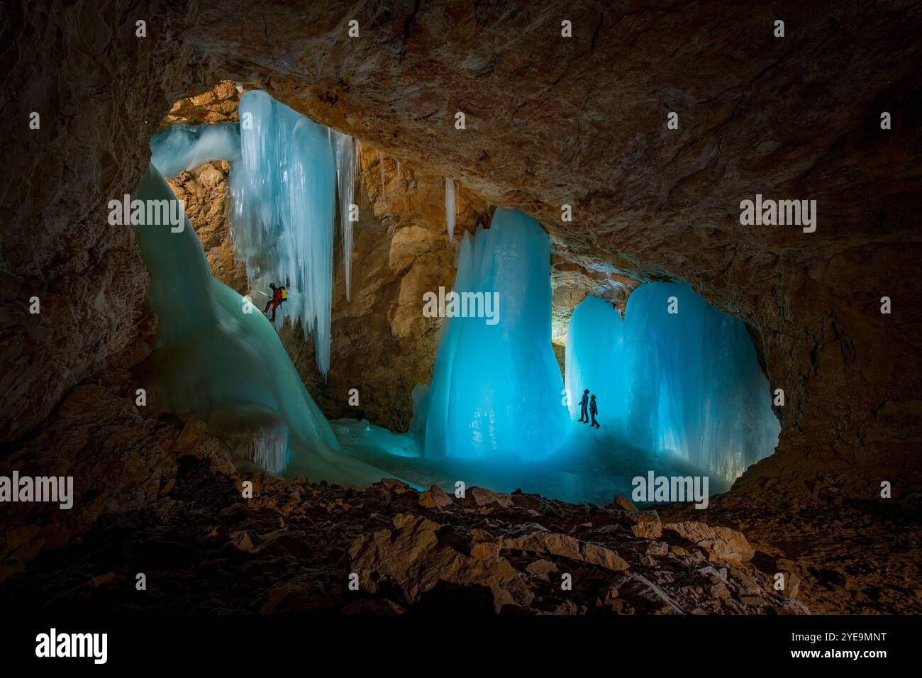 Wissenschaftler der Universität Innsbruck, die an Seilen hängen, während sie Proben von der Eiswand eines Gletschers in einer beleuchteten Eishöhle sammeln... Stockfoto