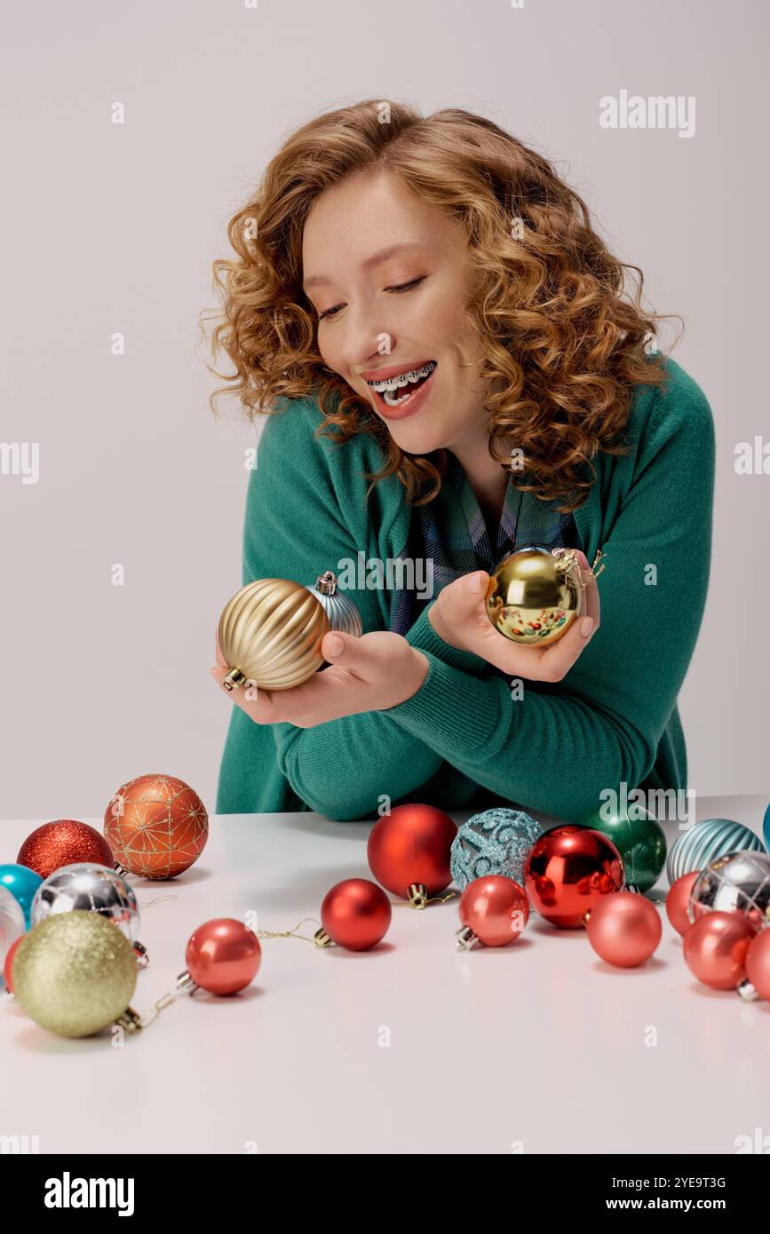 Eine junge Frau mit lockigem Haar posiert glücklich, umgeben von festlichen Ornamenten. Stockfoto