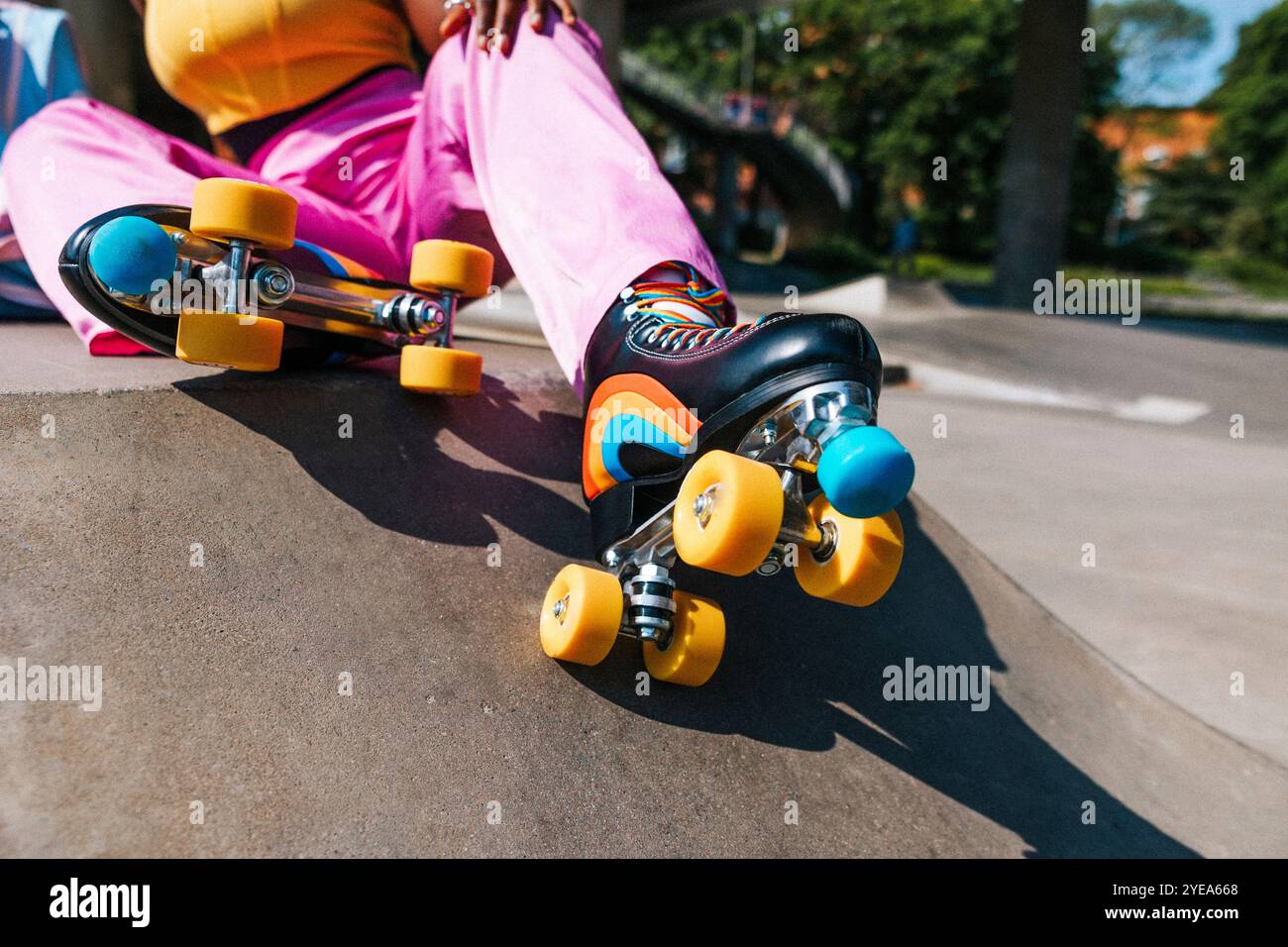 Frau trägt Rollschuhe mit gelben Rädern und Regenbogenstreifen Stockfoto