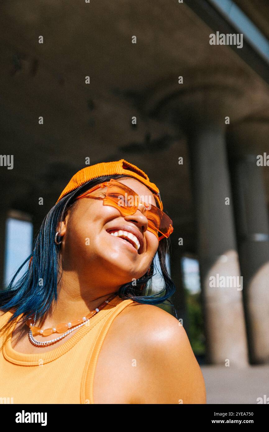 Glückliche junge Frau in Mütze und Sonnenbrille am sonnigen Tag Stockfoto
