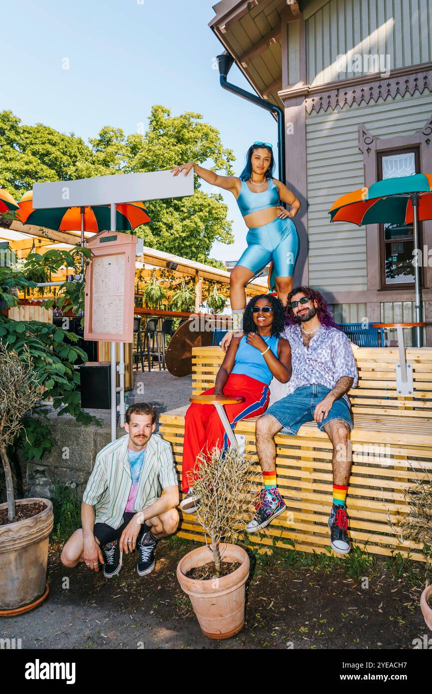 Porträt multirassischer Freunde, die auf der Bank vor dem Restaurant posieren Stockfoto