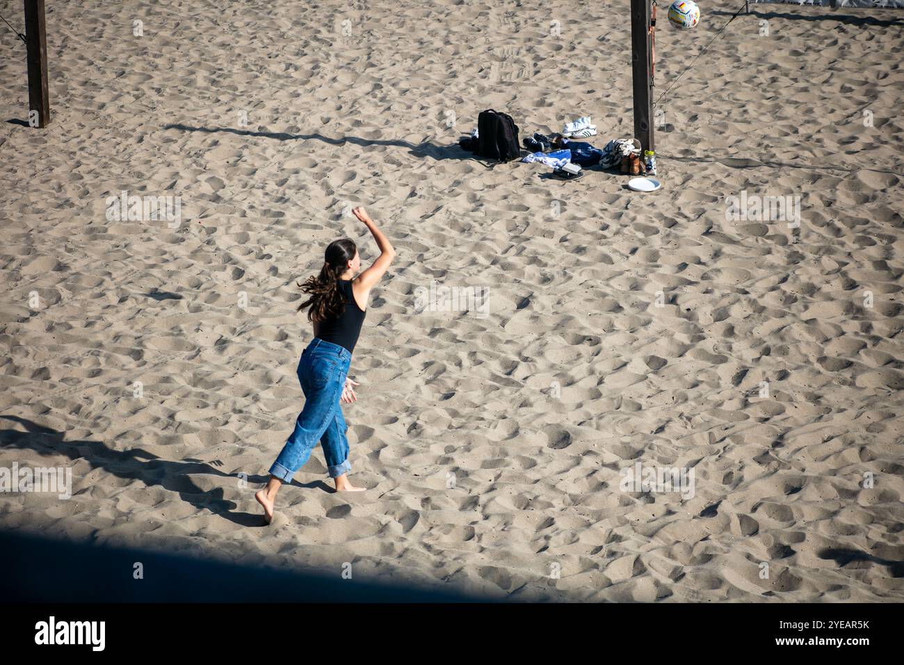 Ungezwungene Beachvolleyballspieler, die den Tag genießen und die Leute mit dem Ball auf dem Sand beobachten Stockfoto