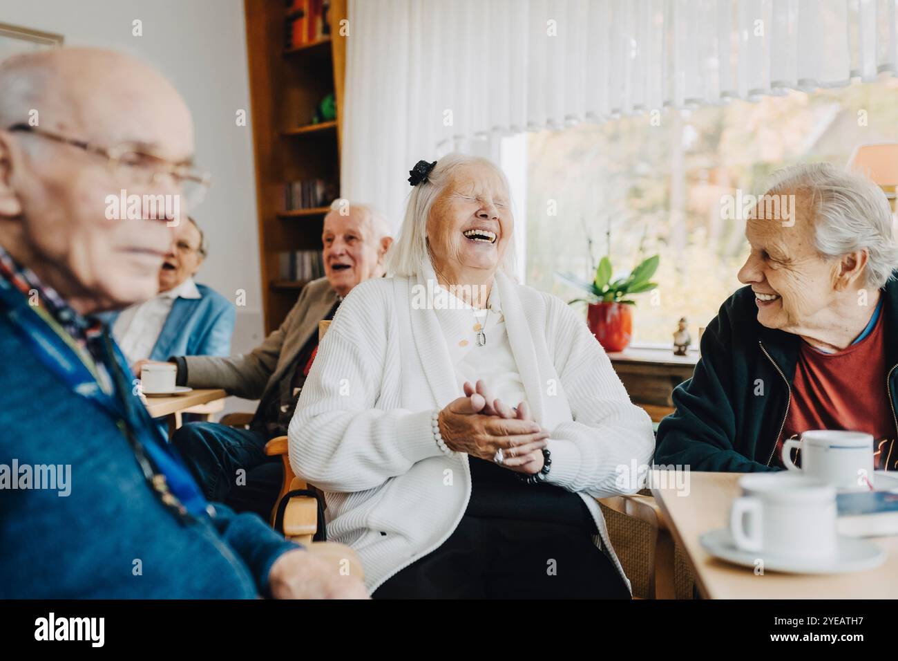 Glückliche Seniorinnen und Senioren, die ihre Freizeit genießen, während sie sich im Altersheim miteinander unterhalten Stockfoto
