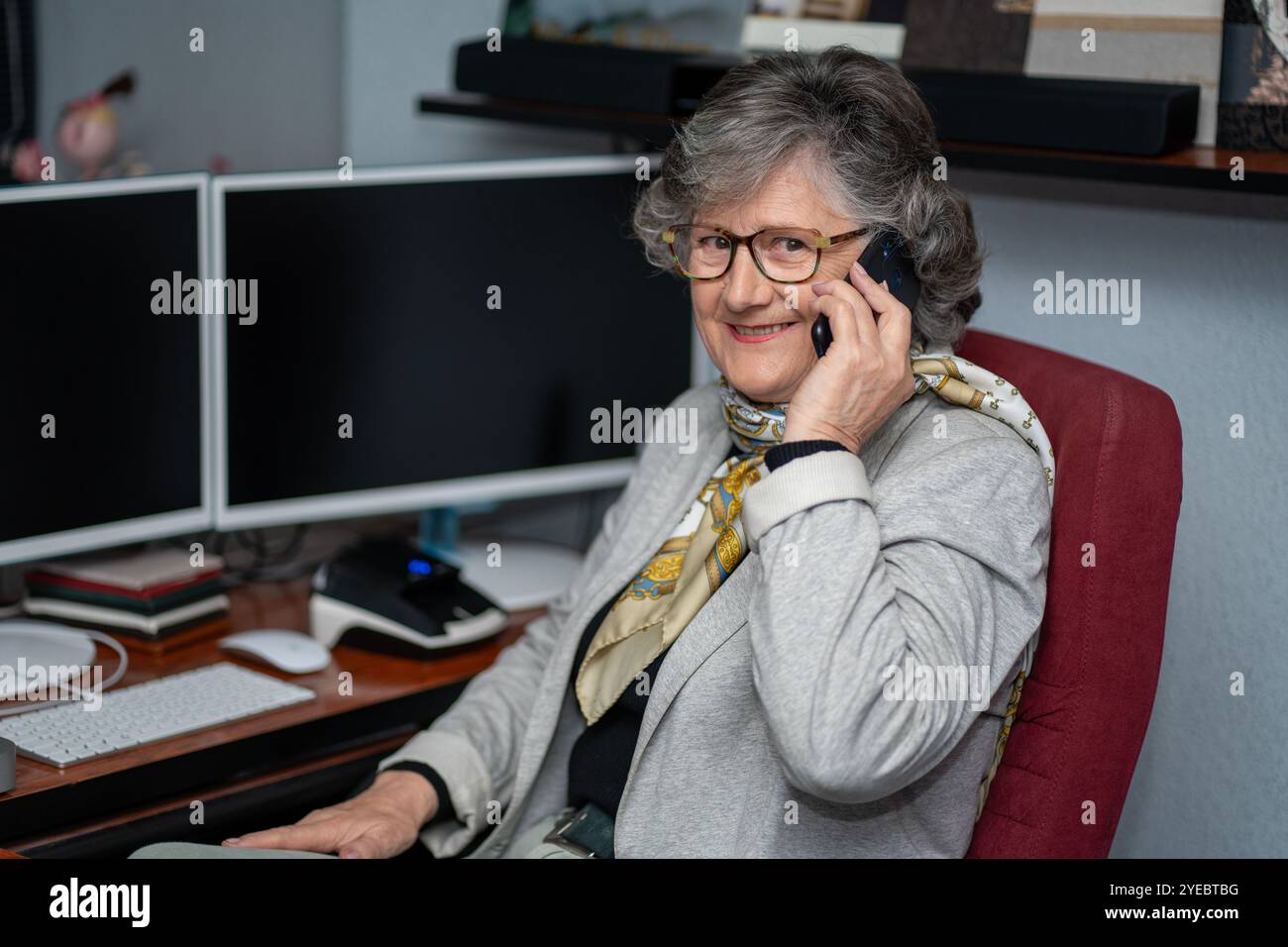 Reife grauhaarige Geschäftsfrau, die ein lächelndes Telefongespräch führt Stockfoto