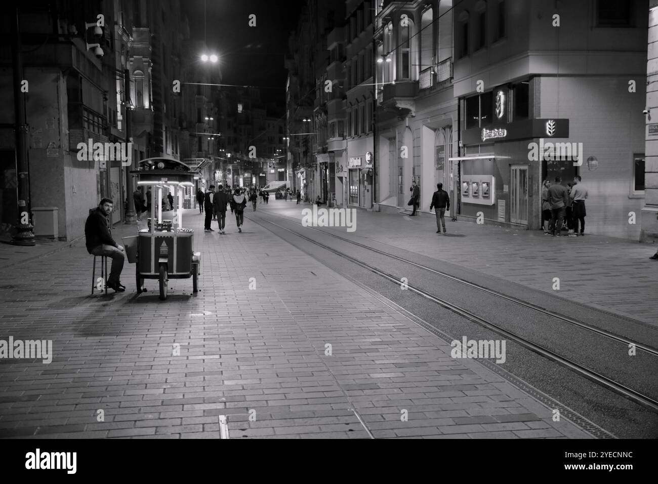 Ein Straßenverkäufer verkauft von seinem Wagen unter einem sanften Schimmer aus Schatten und warmem Licht, das sich in das lebhafte, aber ruhige Ambiente Istanbuls verschmilzt Stockfoto