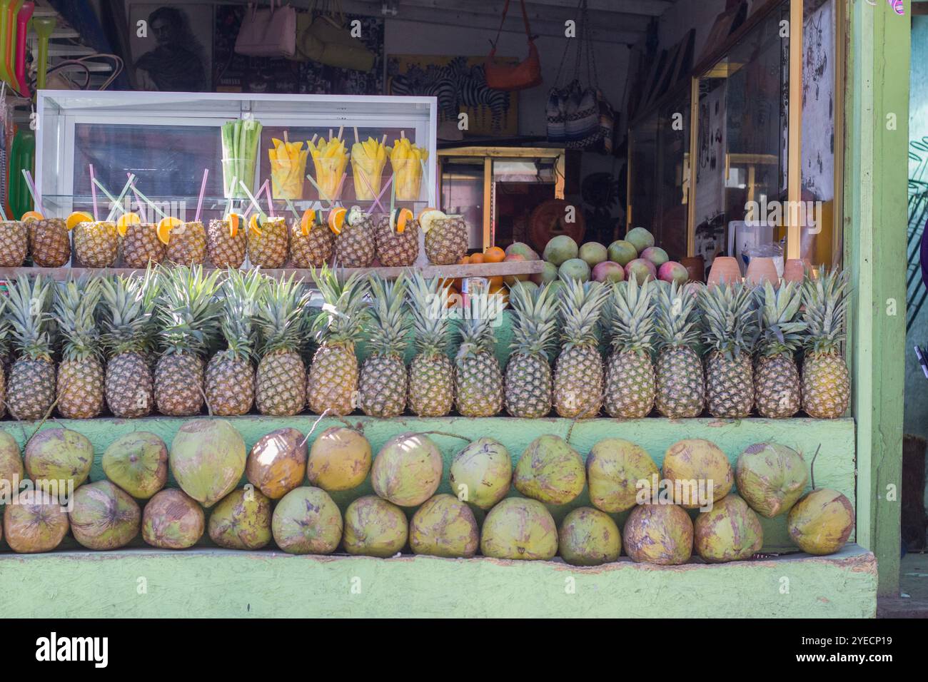 Ein lebhafter Straßenstand mit grünen und gelben Früchten, gefüllt mit frischen Ananas und Kokosnüssen, schafft eine lebhafte, tropische Atmosphäre an sonnigen Tagen Stockfoto